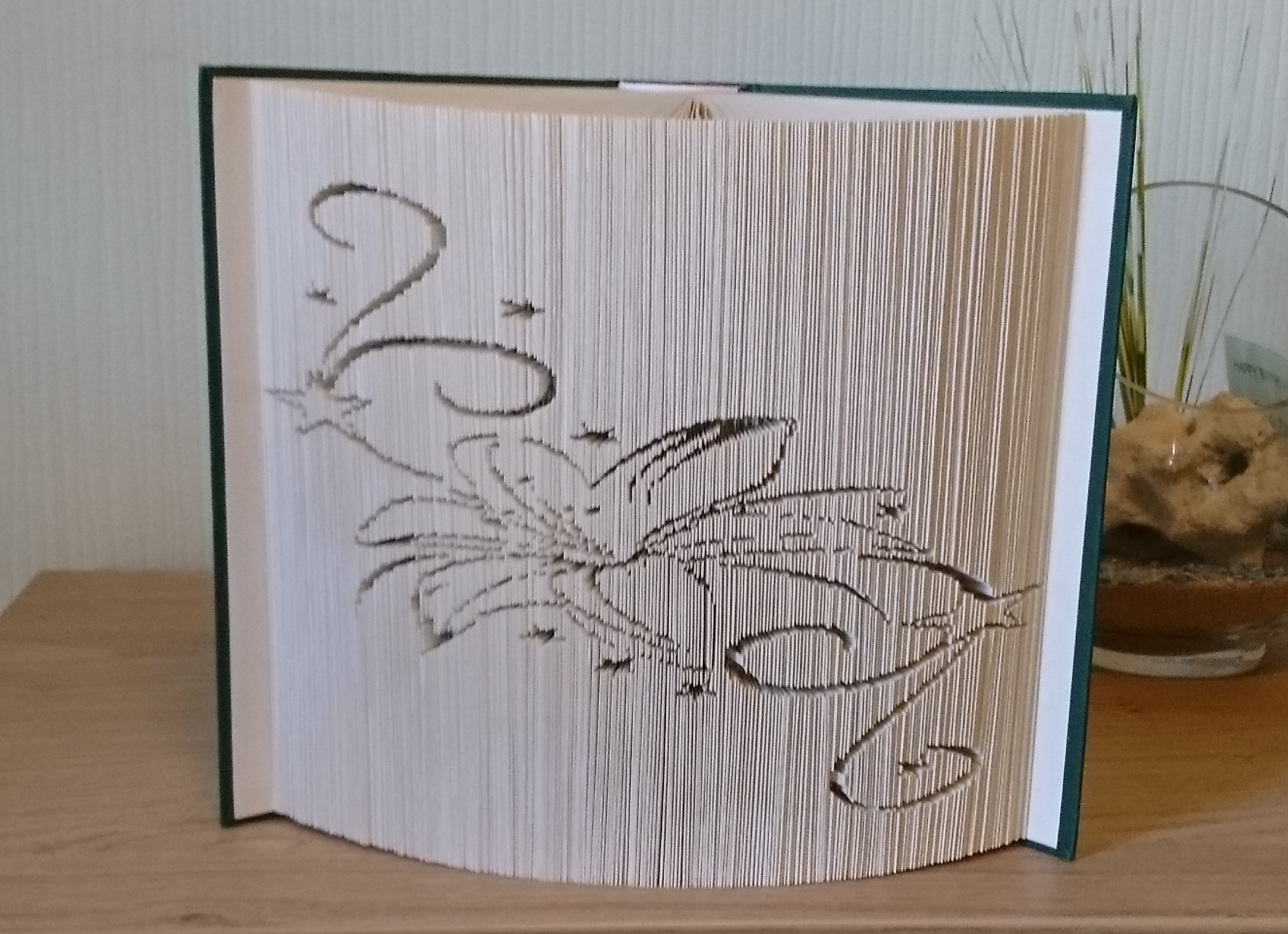 Aufgeklapptes Buch in dessen Seiten eine Lilie geschnitten wurde und einige Stern